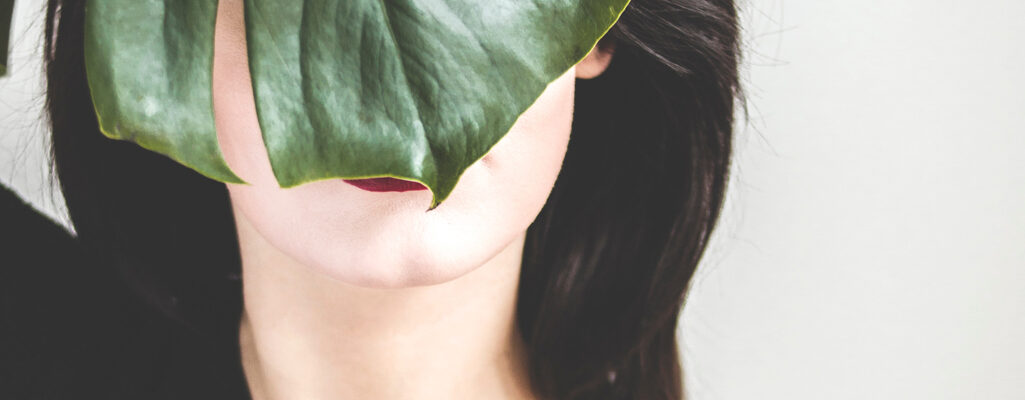image of a brunette with a leaf in front of her face.