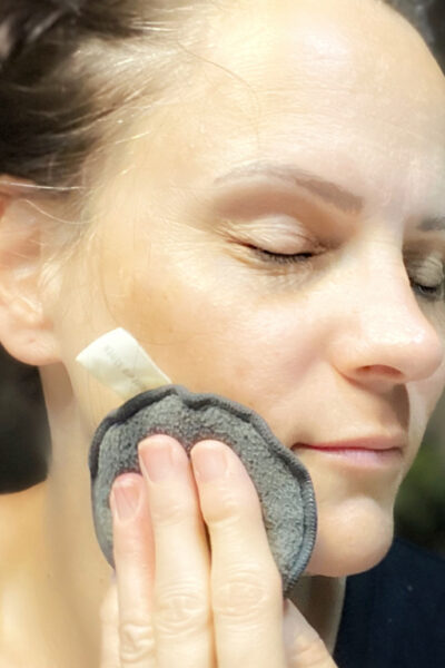image of woman washing her face with a cleansing sponge