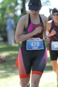 Woman running with a black and orange triathlon suit on